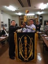 大阪・粟飯原会長(左)から来年の大会ホスト役、京都・山下会長に研究会旗を…